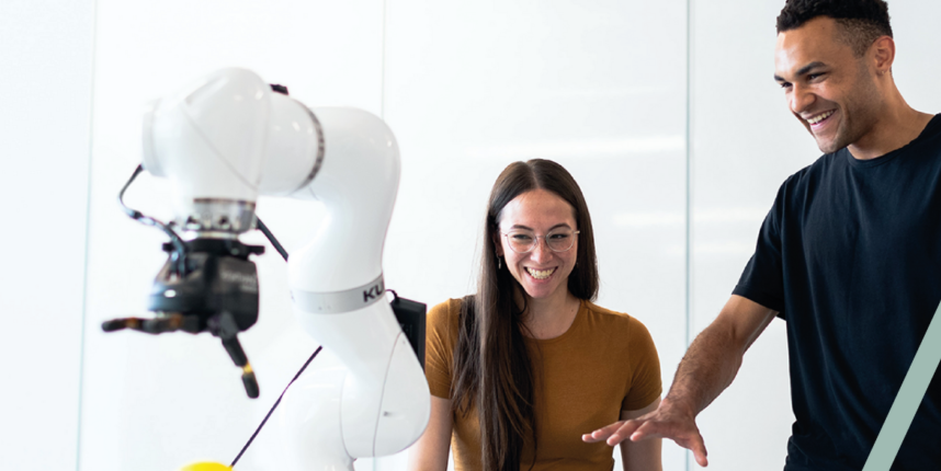 Dos profesionales aprendiendo a programar un brazo robótico